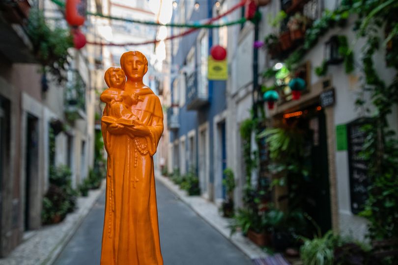  Statuette of Saint Anthony with Jesus. Background: Street with festive decorations
