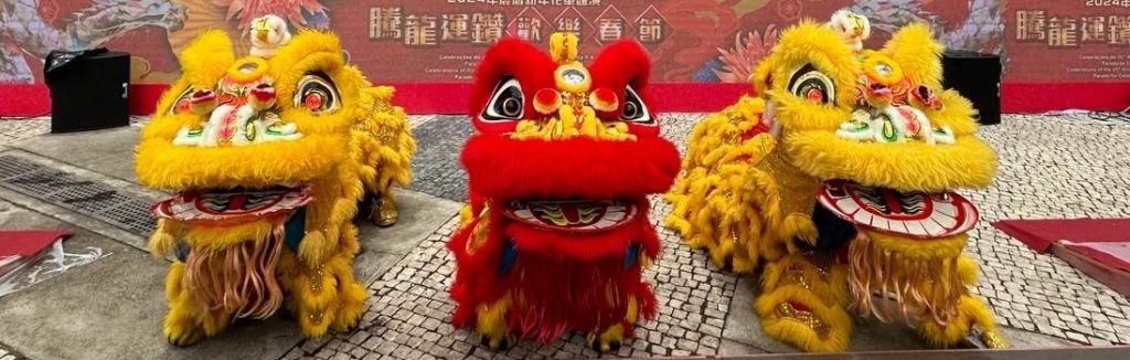 palco com muitas pessoas em trajes populares. 3 grandes dragões à frente