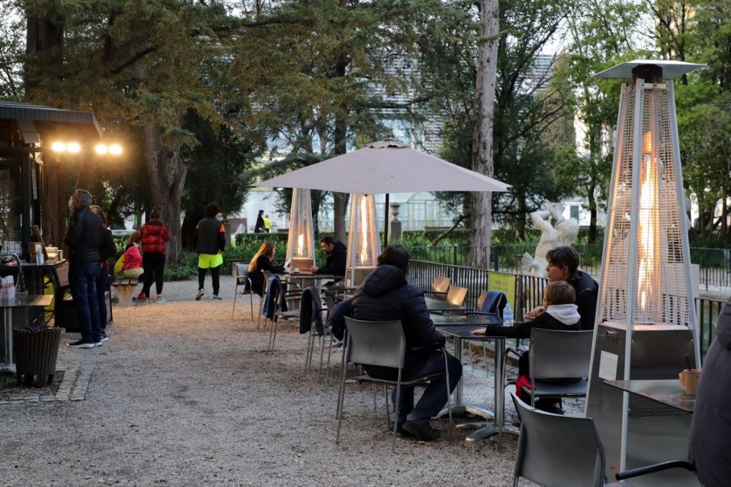 Esplanada com aquecedores e guarda-sol; pessoas sentadas nas mesas.