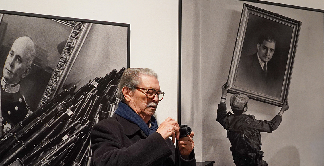 Eduardo Gageiro com máquina fotográfica à frente das suas fotografias expostas
