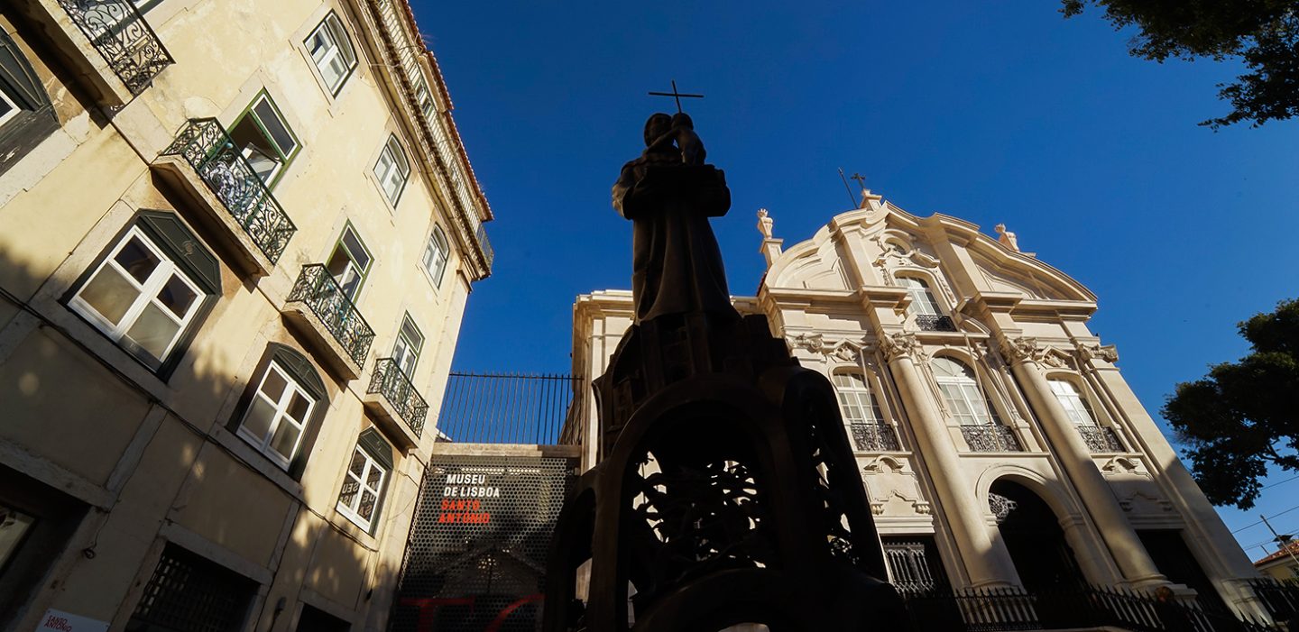estátua de Santo António numa praça com igreja e Museu
