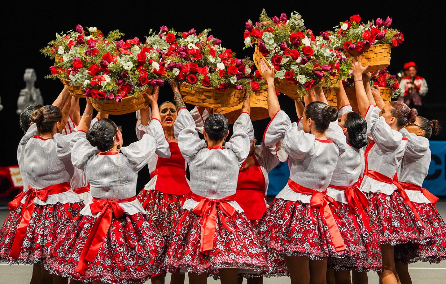 grupo de mulheres com trajes coloridos com cestas cheias de rosas