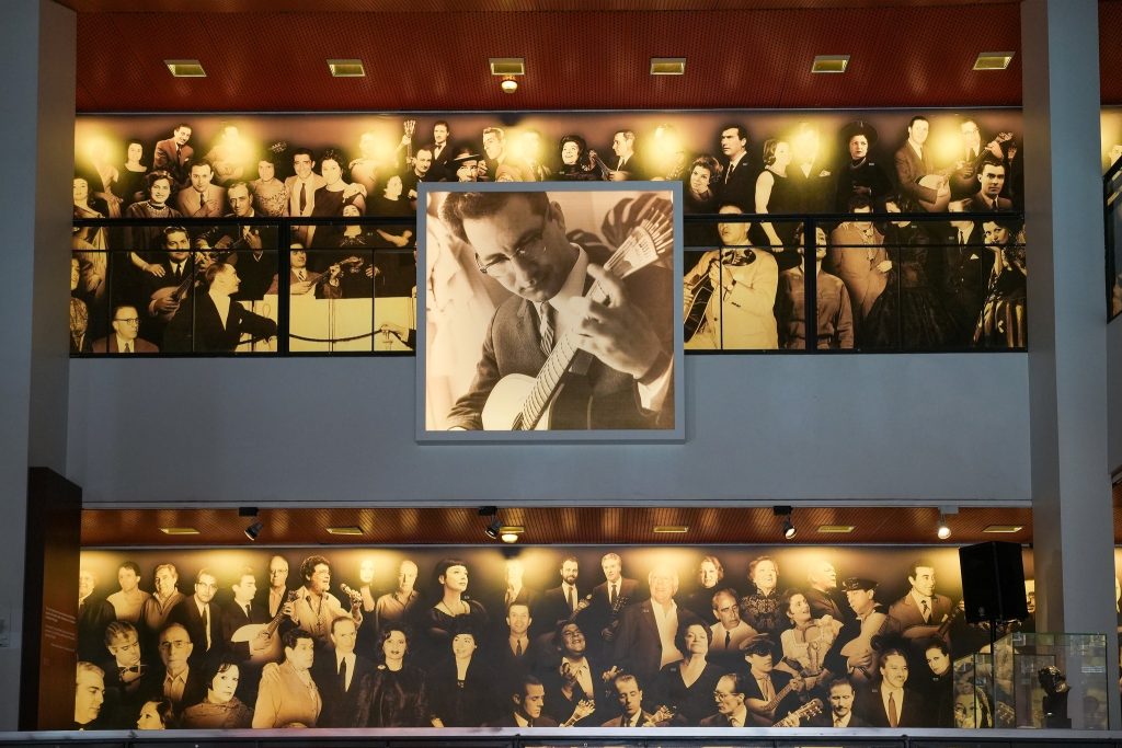 2 pisos com papel de parede com muitas figuras do fado. No entrepiso grande quadro com imagem de Carlos Paredes