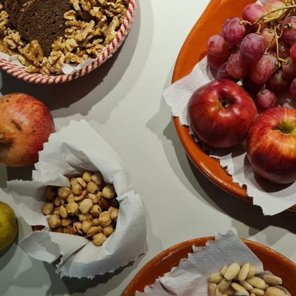 Sobre um fundo branco, taças de barro com nozes, amêndoas, avelãs, uvas, maçãs e romãs