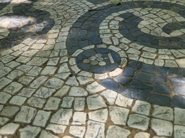 Calçada portuguesa, com pedras pretas e brancas, vendo-se uma cacho de uvas desenhado