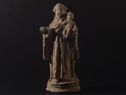 Imagem de uma estátua de Santo António sob um fundo preto